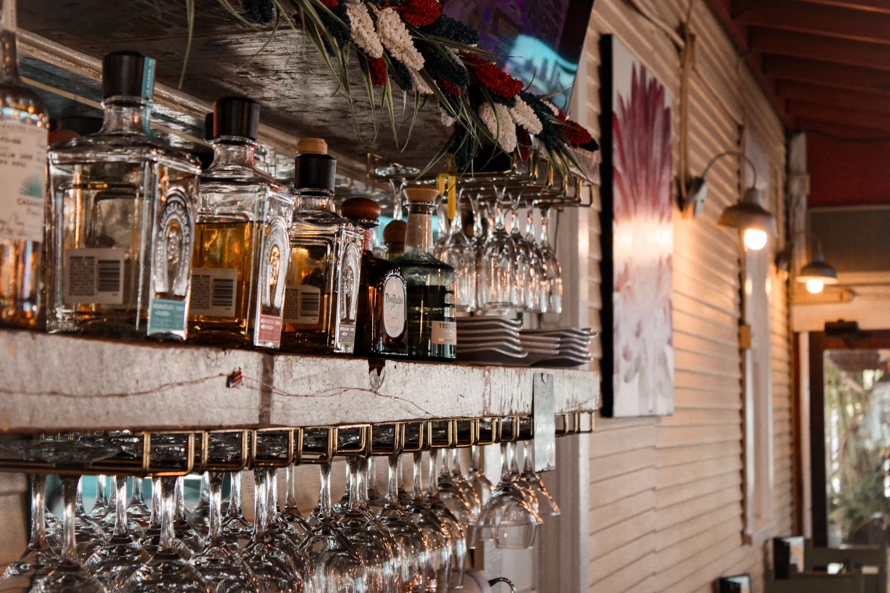 Tequila bottles and hanging glassware at El Jardín's bar
